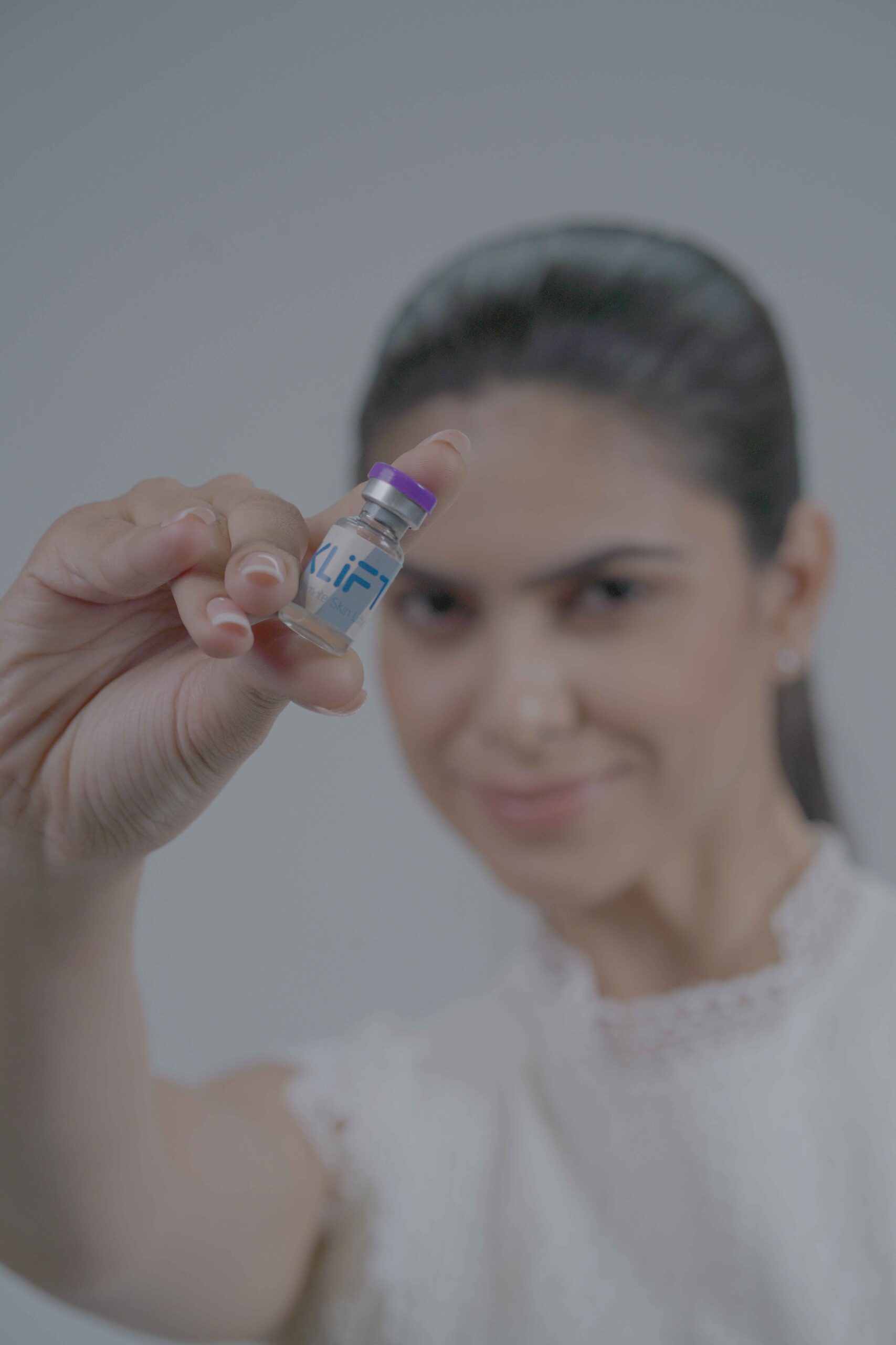 امرأة تحمل قارورة معزز البشرة KLIFT